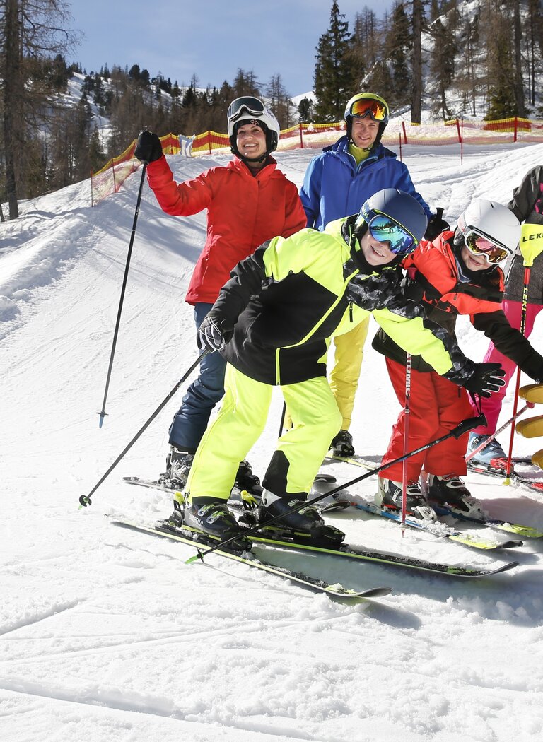 Family skiing on the Galsterberg Fun Run with a yellow high-five hand feature in the snow and clear blue sky. | © Galsterbergalm Bahnen GmbH & Co KG 