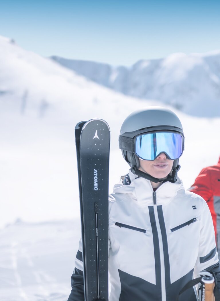 Two skiers in modern gear stand on a snowy slope, wearing helmets and goggles, ready to start their run in Ski amadé mountains. | © Ski amadé GmbH